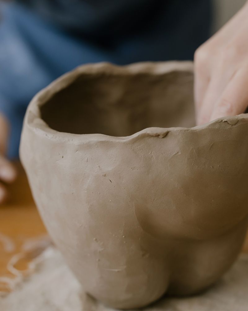 A ceramicist shaping a clay pot on a workbench
